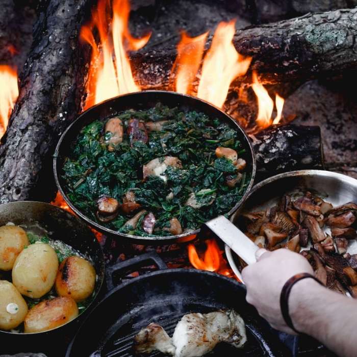 people enjoy cooking over a campfire