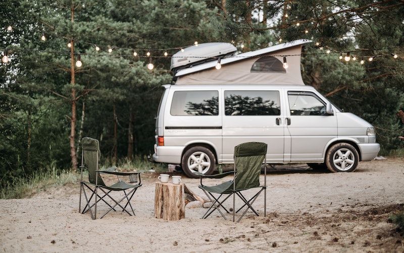 a van in the woods near camping chairs