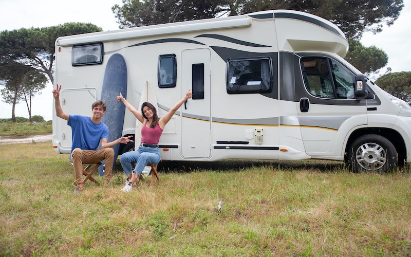 two people sitting in front of an RV at a campground