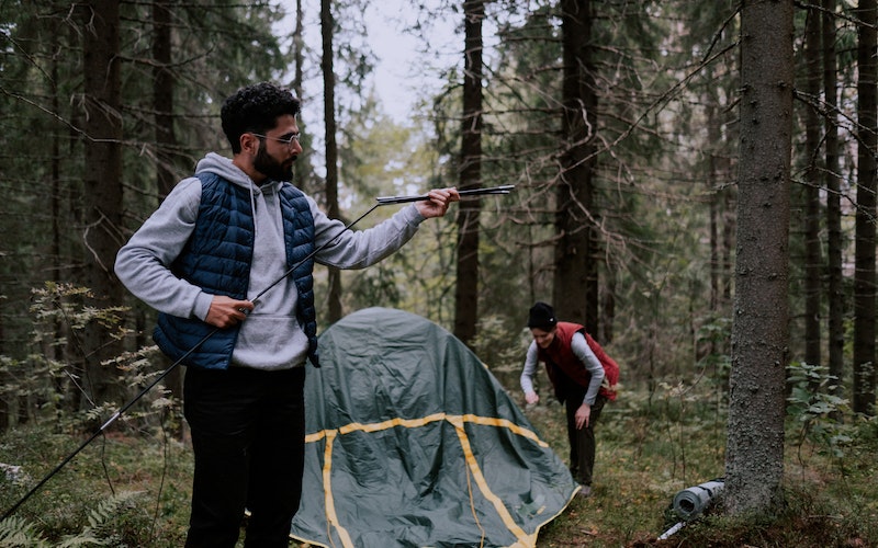 a man putting a tent up deep in the woods